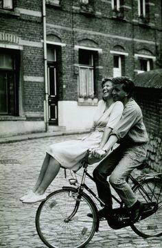 a man riding on the back of a bike next to a woman