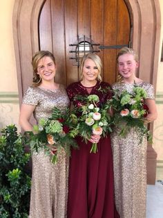 three women in long dresses holding bouquets standing next to each other near a door