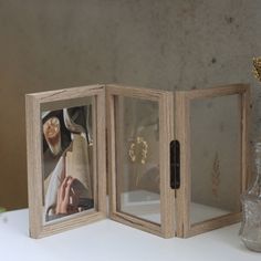 an open book with pictures inside on a table next to a vase and glass bottle