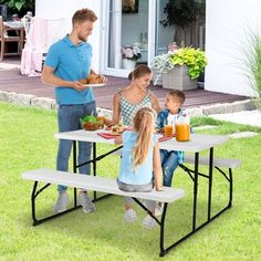 a man and two children sitting at picnic tables with food on the table in front of them