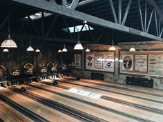 an old bowling alley with wooden floors and lights hanging from the ceiling, along with several bowling pins lined up in rows