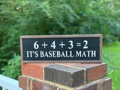 a sign that says it's baseball math on top of a brick pillar in front of some trees