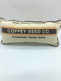 a pillow that says coffee seed co on the front and back of it, with an orange stripe down the middle