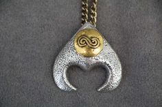 a gold and silver pendant with a spiral design on it