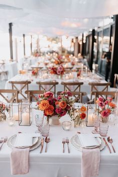 a long table with white linens and candles is set for an elegant wedding reception