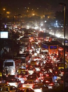 a busy city street filled with lots of cars and buses at night, all in traffic