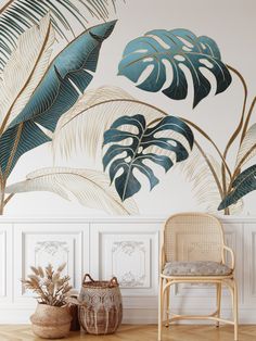 a chair and potted plant in front of a wall with tropical leaves on it