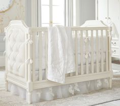 a white crib with a blanket on top of it in front of a window