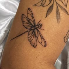 a black and white photo of a dragonfly tattoo on the back of a woman's leg