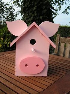 a pink pig house sitting on top of a wooden table