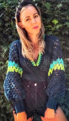 a woman wearing a blue crochet sweater with green trim