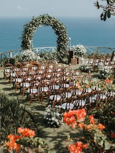 an outdoor ceremony set up with chairs and flowers on the lawn by the ocean is ready for guests to sit down