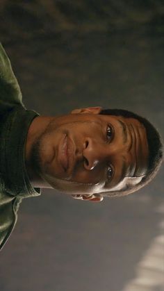 a close up of a person wearing a green shirt and holding a cell phone in his hand