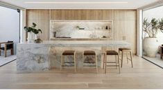 a kitchen with marble counter tops and stools in front of an open floor plan