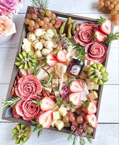 a platter filled with different types of cheeses and fruit on top of a wooden table