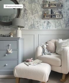 a white chair sitting next to a dresser in a room with a mirror on the wall