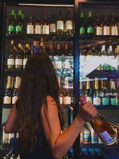 a woman standing in front of a display case filled with bottles and liquors,