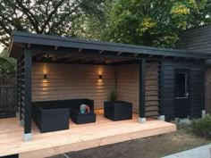 a small wooden building with lights on the roof and some black containers in front of it