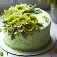 there is a green cake with flowers on the top and bottom layer, sitting on a white table