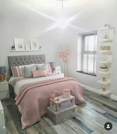 a bedroom with white walls and wooden floors, pink bedding, gray headboard