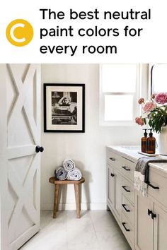 a bathroom with white cabinets and flowers in vases on the sink counter next to an open barn door