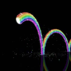 a rainbow colored object floating on top of water in front of a black background with stars