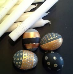 painted eggs sitting on top of a table next to white candles and some paper tubes