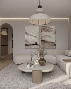 a modern living room with white furniture and artwork on the wall above it, along with an oval coffee table