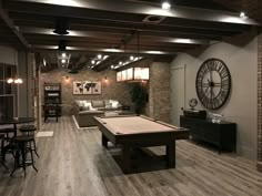 a living room filled with furniture and a pool table in front of a large clock