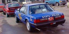 a state police car parked on the side of the road with other cars behind it