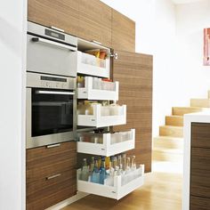 a kitchen with an oven, microwave and stairs in it's storage unit that is open