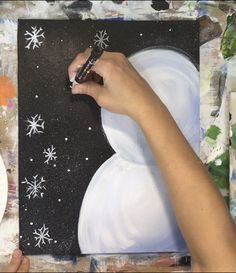 someone is painting snowflakes on a black and white background with paintbrushes