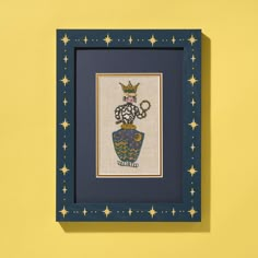 a cross stitch picture hanging on a yellow wall with blue frame and stars around it