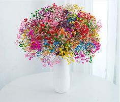 a white vase filled with lots of colorful sprinkles on top of a table