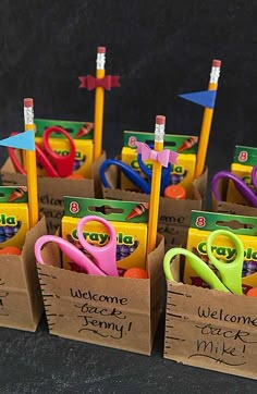 small cardboard boxes filled with different types of scissors and pencils, each containing the word welcome