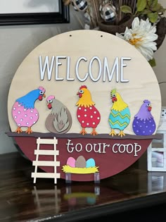 a welcome sign on top of a table with chickens and chicks in the nest below it