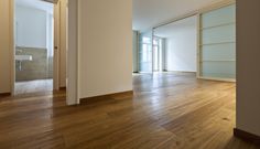 an empty room with wood flooring and white walls in the background is a door leading to another room