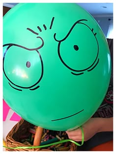 a green balloon with a face drawn on it's side in front of a basket