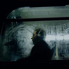 a man sitting on a bus looking out the window at something in the air that is raining