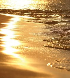 the sun shines brightly through the water at the beach as waves roll in on the sand