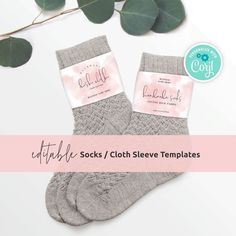 two pairs of socks with labels on them next to eucalyptus leaves and a pink ribbon