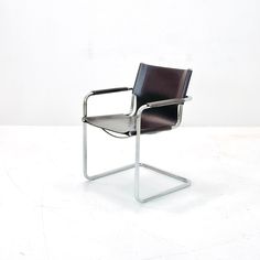 a black leather chair sitting on top of a white floor next to a metal frame