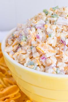 a yellow bowl filled with coleslaw next to crackers