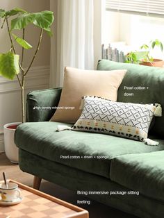 a living room with green couches, pillows and coffee table in front of the window