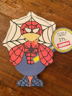 a paper cut out of a spiderman holding a magnifying glass on top of a wooden table