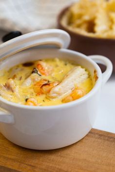 a white bowl filled with food on top of a wooden cutting board