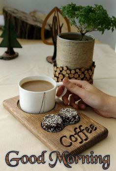 there is a cup of coffee and two donuts on the table with words good morning