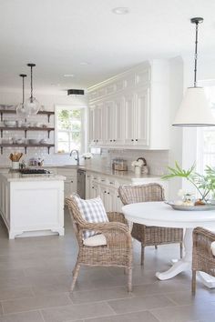 a white kitchen with wicker chairs and an island in the middle is featured on this page