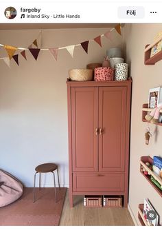 a pink cabinet in the corner of a room with bunting and bookshelves