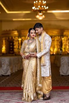 a man and woman standing next to each other in front of a chandelier